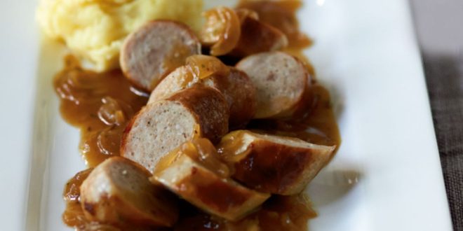 Bratwurst in Zwiebelsauce serviert mit Kartoffeln