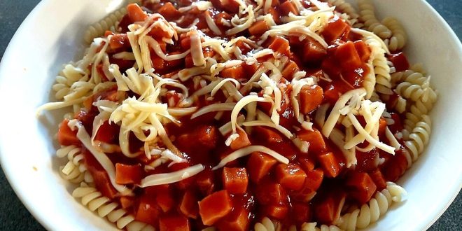 Makkaroni mit Tomatensoße und Geflügelwurst auf Teller serviert