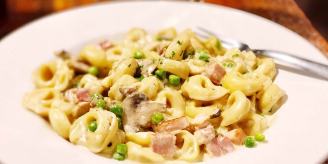 Cremige Toskanische Tortellini mit Spinat, Tomaten und Parmesan in Pfanne serviert