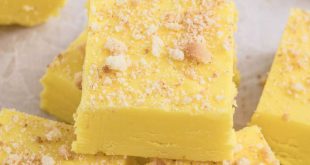 Leuchtend gelbes, cremiges Bananen-Fudge in Quadrate geschnitten und mit Keksbröseln garniert auf einem festlichen Teller.