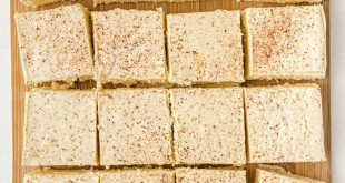 Helle Quadrate von Eierpunsch-Fudge mit Muskatnuss bestreut auf einem weihnachtlichen Teller.