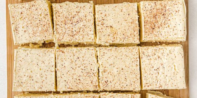 Helle Quadrate von Eierpunsch-Fudge mit Muskatnuss bestreut auf einem weihnachtlichen Teller.