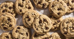 Große, frisch gebackene Chocolate Chip Cookies mit geschmolzener Schokolade auf einem Backblech mit Backpapier.