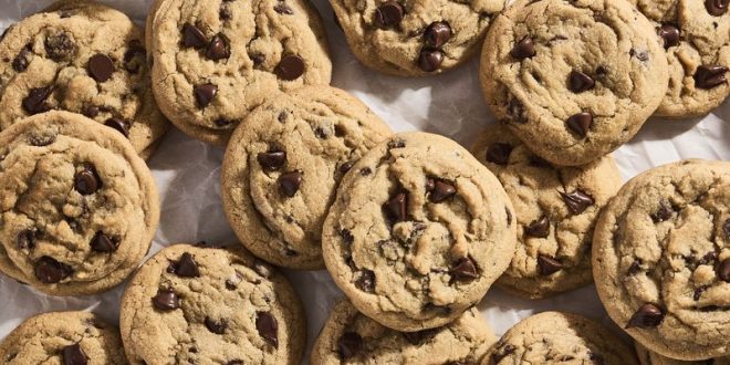 Große, frisch gebackene Chocolate Chip Cookies mit geschmolzener Schokolade auf einem Backblech mit Backpapier.